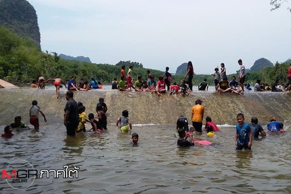 ชาวบ้านแห่กันมาเล่นน้ำที่คลองหนองทะเล ด้วยการสไลด์ตัวหรือการรูดตัวไปตามสันฝาย